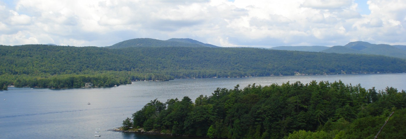 Aerial view of Last Great Shoreline displaying lush green trees with Lake George cutting through the middle.