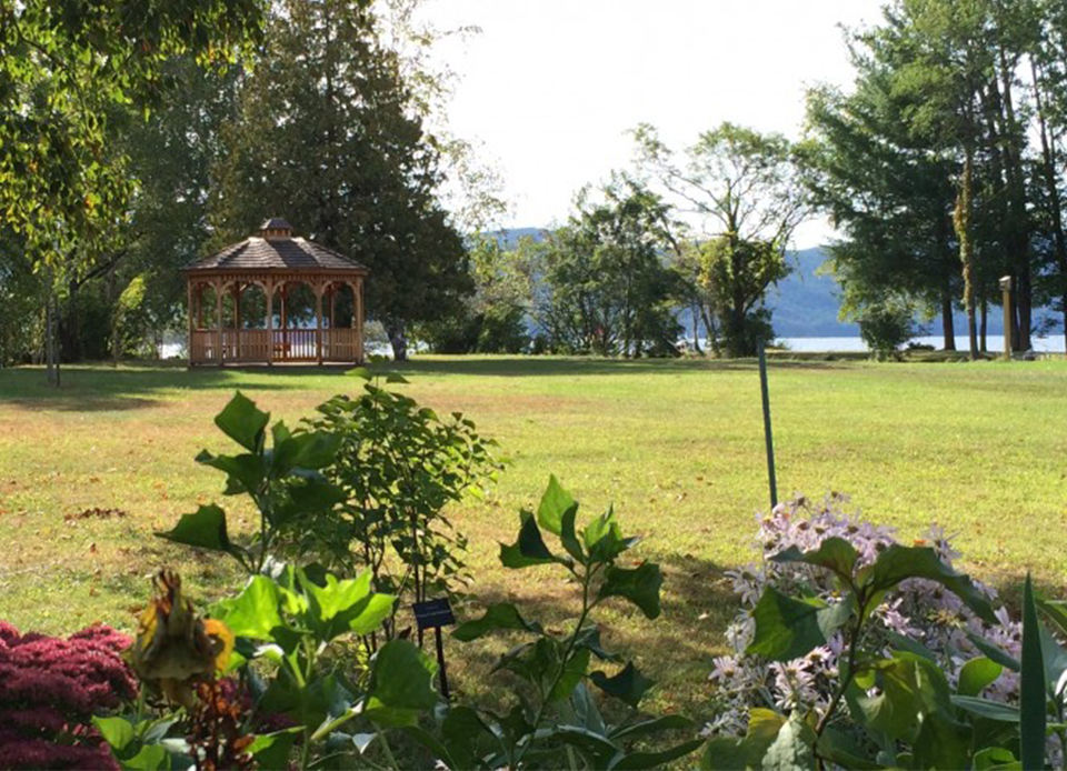A picturesque gazebo nestled amidst a park's greenery and lake in the background.