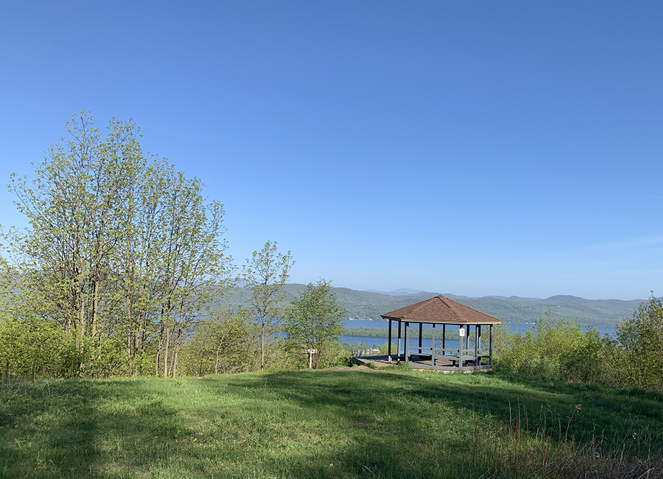 Picturesque gazebo on a hilltop overlooking a serene lake.