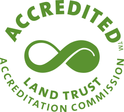 A green circle of text with an infitinity symbol inside of it. The text "Accredited tm" is written above the circle and the text "Land Trust Accreditation Commission" is written inside the cirle.
