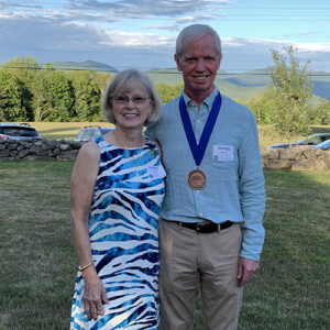 Debbie Hoffman and George Morris stand together, smiling, with a pastoral summer backrgound.