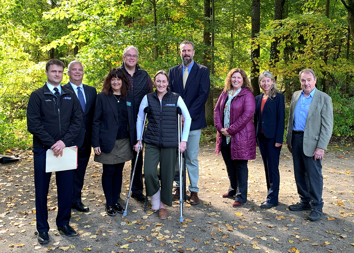 State and local officials, organization leaders, pose in front of a forested background or a group picture during the press conference at Wiawaka.