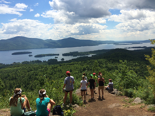 A group of people stand at top of Bradley's Lookout to view Lake George.